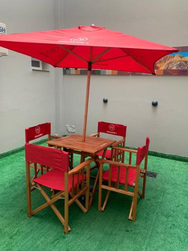 a wooden table with red chairs and a red umbrella at Benjamín I in San Salvador de Jujuy