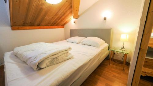 een bed met witte lakens en kussens in een kamer bij Chalet De Florence - 3 Pièces pour 8 Personnes 124 in Modane