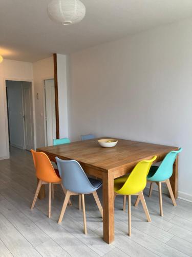 une table à manger entourée de chaises colorées. dans l'établissement Grand appart proche Versailles., à Les Clayes-sous-Bois