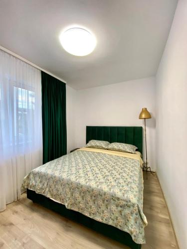 een slaapkamer met een bed met een groen hoofdeinde en een raam bij Mainstreet Apartments Suceava in Suceava