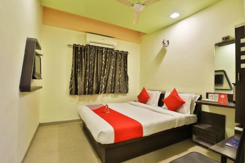 - une chambre avec un lit doté d'oreillers rouges et une fenêtre dans l'établissement Collection O Hotel Santro, à Naroda