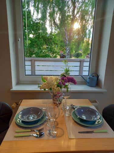 a table with plates and glasses in front of a window at Luhe Idyll in Luhdorf