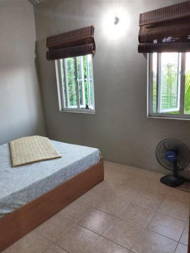 1 Schlafzimmer mit einem Bett, 2 Fenstern und einem Ventilator in der Unterkunft Villa Belle in Port Louis