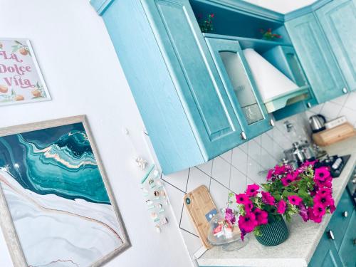 a kitchen with blue cabinets and a vase of pink flowers at JCK Tuscany Apartment in Livorno