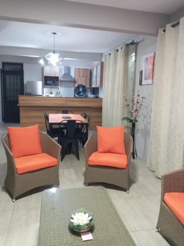a living room with chairs and a table and a kitchen at Villa Belle in Port Louis