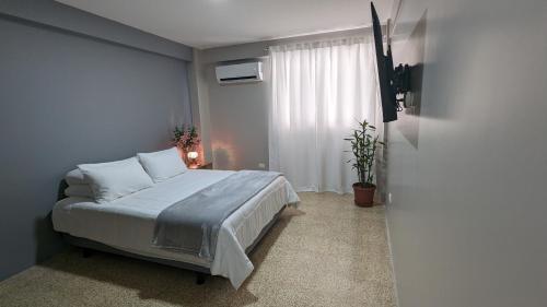 a bedroom with a bed with white sheets and a window at Suite 618 Downtown Guayaquil- Centro de la Ciudad in Guayaquil
