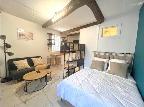 a bedroom with a bed and a couch and a table at Le Viala, Studio dans le centre historique de Hyères in Hyères