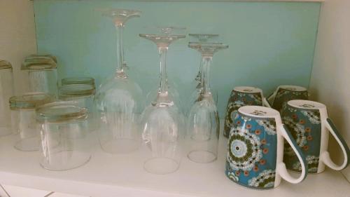 un montón de jarrones de cristal y tazas en un estante en Down By The Sea, the beachfront Apartment, en Puerto Coyote