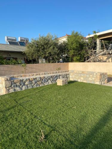 a yard with a stone retaining wall and a green lawn at The Dona House in Vaia