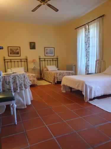 a bedroom with two beds and a red tiled floor at Hotel Rural El Vaqueril in Navas del Madroño