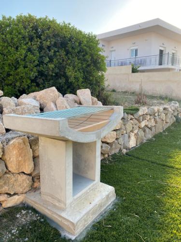 a stone bench in a yard with a rock wall at The Dona House in Vaia