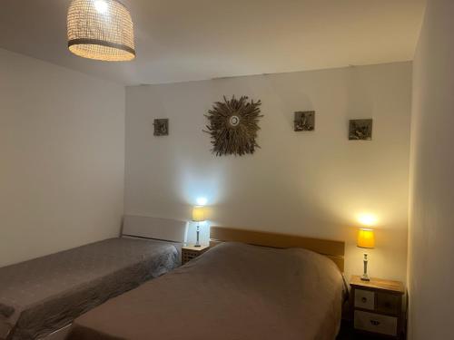 a bedroom with two beds and two lights on the wall at Les Oliviers CENTURI-PORT in Centuri