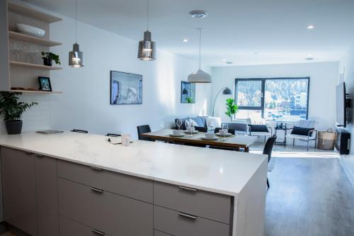 a kitchen with a white counter and a dining room at Birdies and Bears by Revelstoke Vacations in Revelstoke