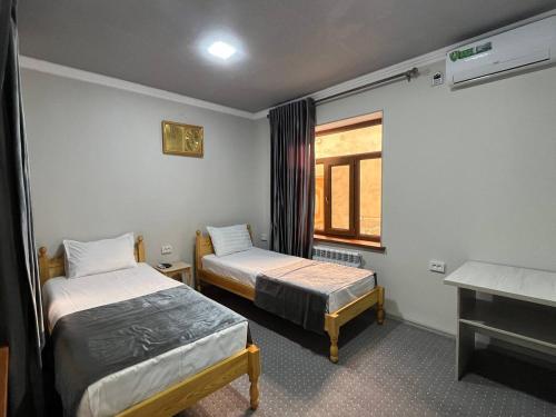 a small room with two beds and a window at ALIXAN Hotel in Bukhara