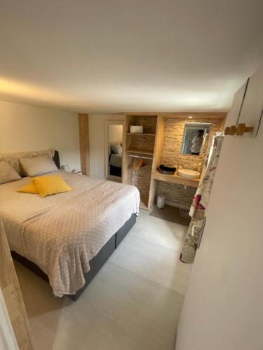 een slaapkamer met een bed en een badkamer met een spiegel bij Le Petit Papillon in Durbuy