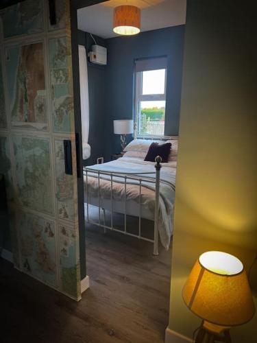a bedroom with a bed with a lamp and a window at The Stables at Ballyward Croft in Ardkeen