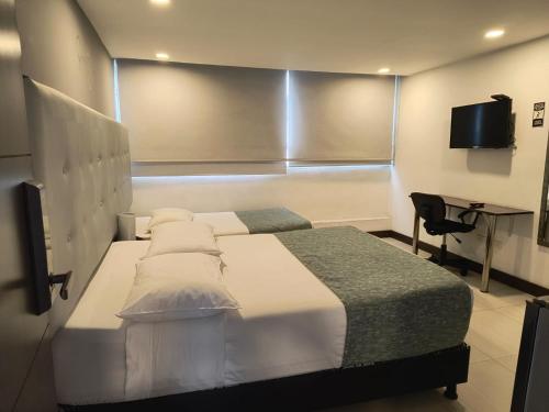 Dormitorio con cama, escritorio y TV en Aw Hotel Serenity Ferial, en Bogotá