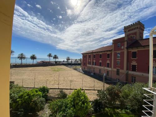 a building with a field and palm trees in the background at Dreaming of the Sea Albenga View in Albenga