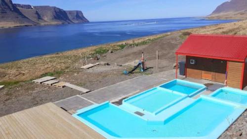 a man standing next to a building with two swimming pools at Guesthouse Tálknafjörður in Talknafjordur