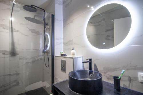 uma casa de banho com um lavatório e um chuveiro com um espelho. em appartement face mer em La Baule
