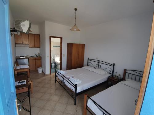 a bedroom with two beds and a desk and a kitchen at Amodari studios on the beach in Plaka
