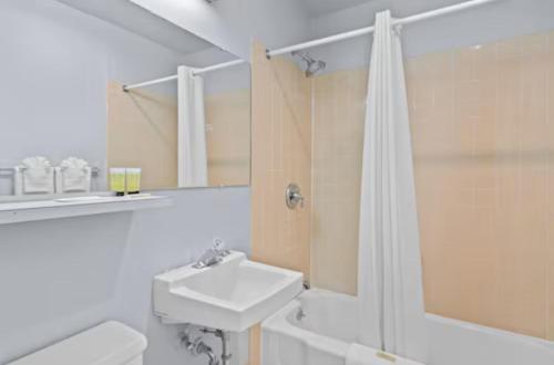 uma casa de banho branca com um lavatório e um chuveiro em Holiday Lodge em Wenatchee