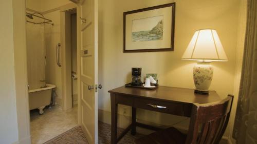 a room with a desk with a lamp and a bathroom at Hotel Arcata in Arcata