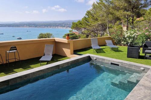 - une piscine avec des chaises et une vue sur l'eau dans l'établissement Grande maison climatisée piscine en bord de mer, à Saint-Cyr-sur-Mer