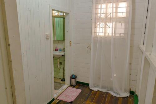 SMITH'S BNB ROOMS 2 في جورج تاون: حمام بجدران بيضاء ومغسلة ومرآة