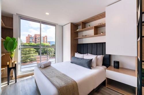 een slaapkamer met een groot bed en een groot raam bij gAº Maravilloso apartamento en zona T in Bogota