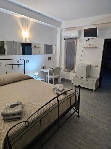 Un dormitorio con una cama, un escritorio y un televisor. en B&B Santa Vener, en Vibo Valentia Marina