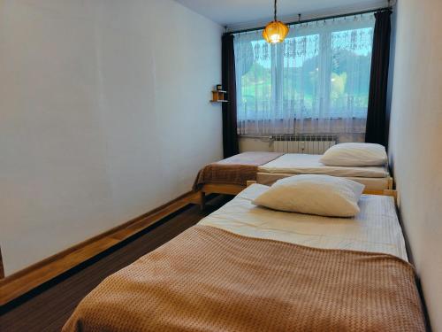 three beds in a room with a window at Słoneczny Zakątek in Jaworki