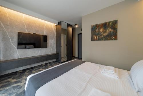 a bedroom with a bed and a tv on a wall at Apartmani 8 Beograd in Jajinci