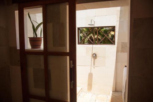 a bathroom door with a shower and a potted plant at Zen Resort Bali in Umeanyar