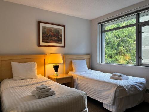 two beds in a room with a window at Carey Centre in Vancouver