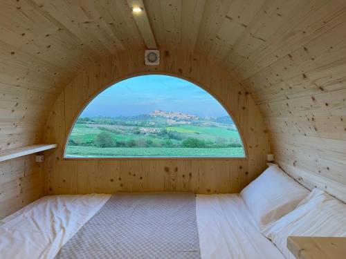 a small bedroom with a window in a wooden room at Notte nella Botte in Olivola