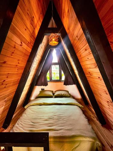 a bed in a wooden attic room with a window at Joy Sapanca in Sapanca