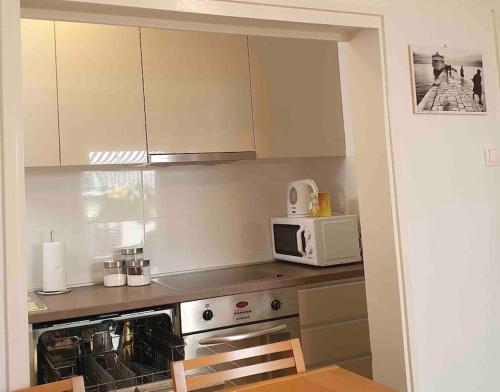 a kitchen with white cabinets and a microwave at Apartman Zvonimir with a beautiful sunset in Silba