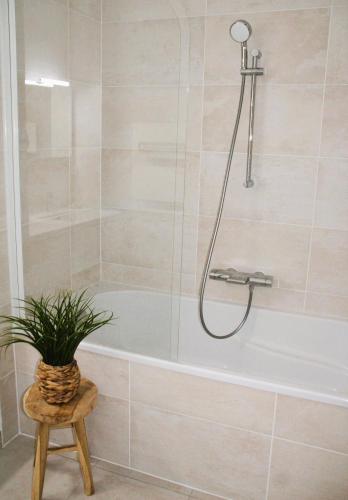 La salle de bains est pourvue d'une baignoire et d'une plante sur un tabouret. dans l'établissement La Madrague - front de mer, accès privé plage et place de parking, à Roscoff