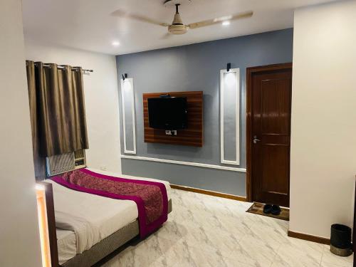 1 dormitorio con 1 cama y TV de pantalla plana en Royal Presidency Inn, en Lucknow