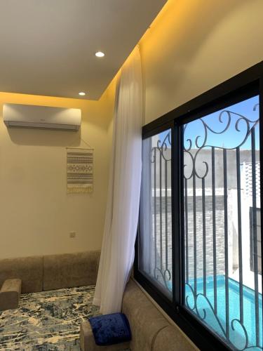 um quarto com uma grande janela com um sofá e uma varanda em فيلا رسن em Al Hada
