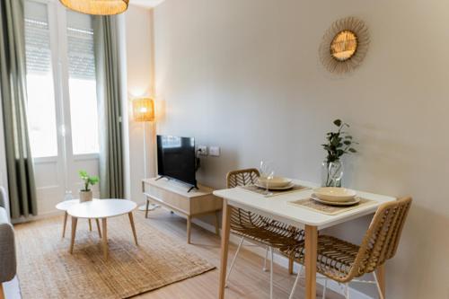 a living room with a table and chairs and a tv at L'élégant - Beau logement avec vue Sarthe - Gare - Tram - Centre ville in Le Mans