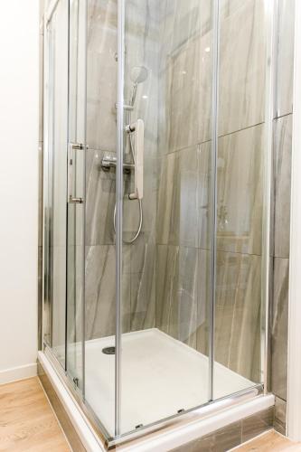 une douche avec une porte vitrée dans une salle de bain dans l'établissement L'élégant - Beau logement avec vue Sarthe - Gare - Tram - Centre ville, au Mans