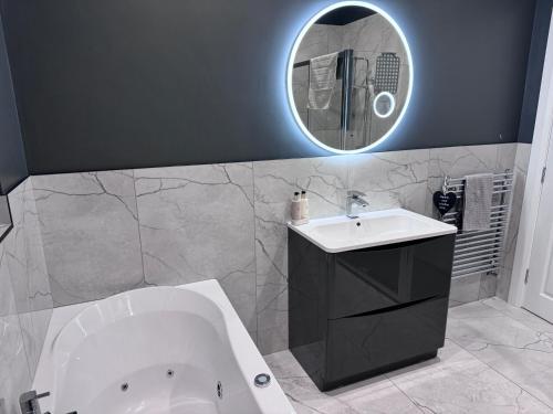 een badkamer met een bad, een wastafel en een spiegel bij Sheriffs Mountain Lodge in Derry Londonderry