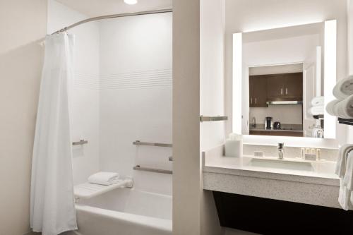 a bathroom with a tub and a sink and a mirror at TownePlace Suites Cedar Rapids Marion in Marion
