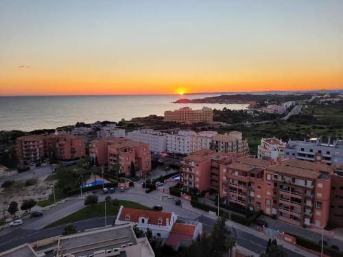 a sunset over a city with buildings and the ocean at O WOW View Portimao, ALvor, ALGARVE in Portimão
