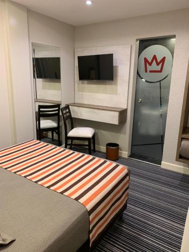 a hotel room with a bed and chairs and a television at Benjamín I in San Salvador de Jujuy