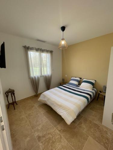 a bedroom with a large bed with blue and white sheets at L'hérisson LOPIC in Cours-de-Pile