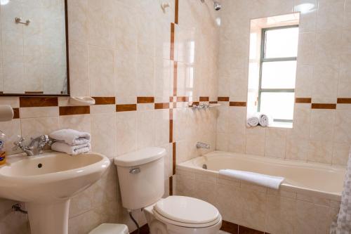 a bathroom with a toilet and a sink and a tub at Hospedaje La Florida in Urubamba