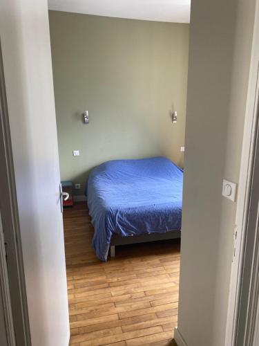 een slaapkamer met een bed met blauwe lakens en een houten vloer bij Apt 1 ch - Centre ville Vannes - Gare à pied - Parking in Vannes